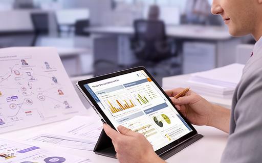 Consulente HR in ufficio che analizza documenti con un tablet, affiancato da grafici e report sul personale